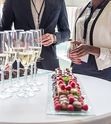 two business people standing in front of a table with champagne glasses and fruit platter