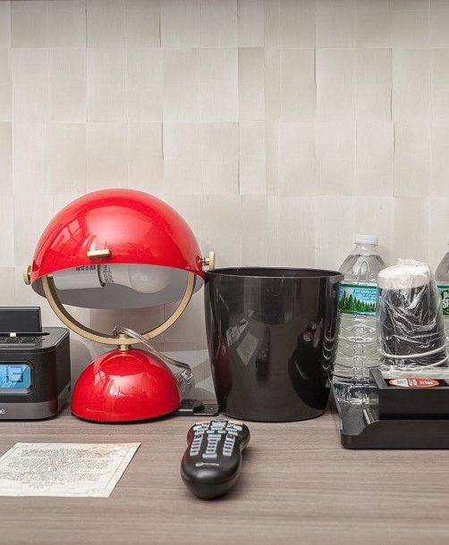 desk area with a coffee machine, alarm clock, phone, water, and remote