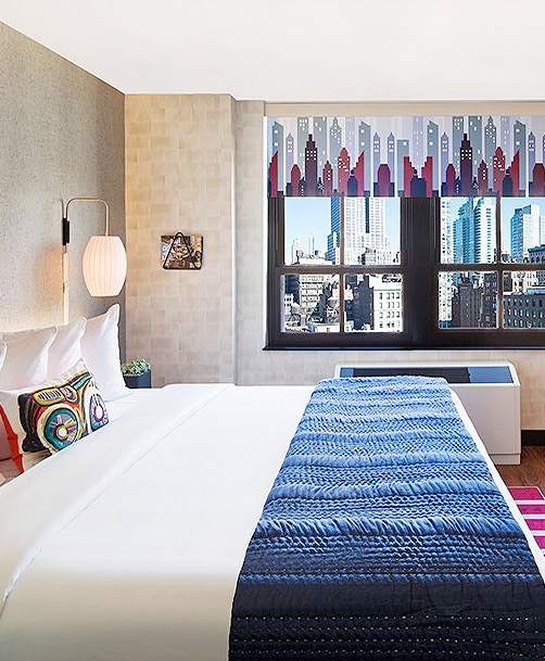 guest room with white linens, navy bleu end blanket, and view of downtown city