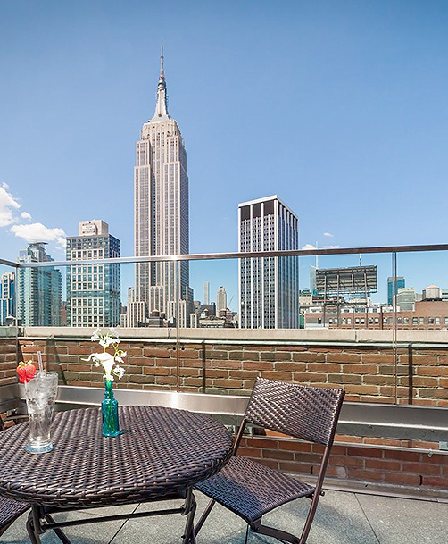 rooftop patio with a patio table and chairs overlooking the empire state building 